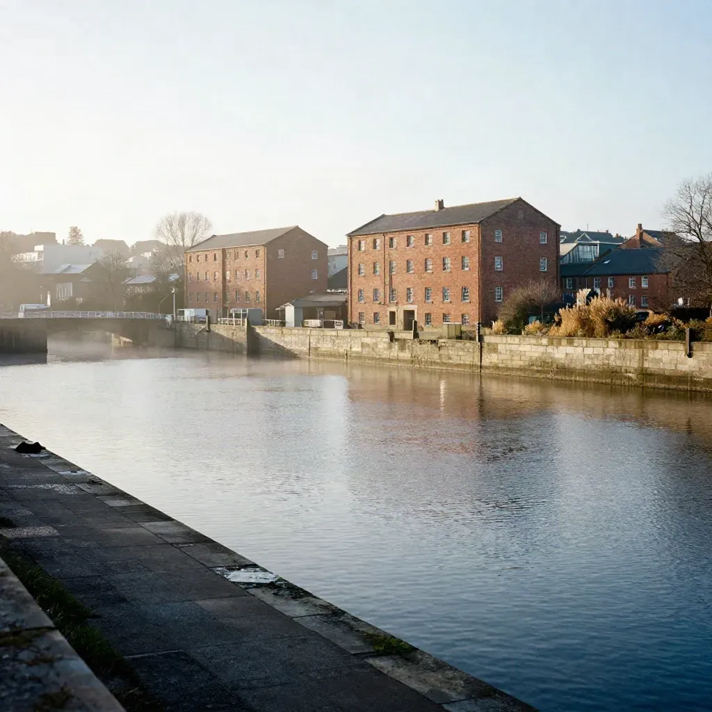 Hazy North West England dock basin with red-brick mills and calm water for copy space.